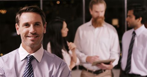 Confident Businessman Smiling with Team Collaborating in Background - Download Free Stock Images Pikwizard.com