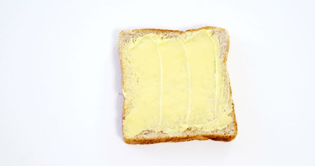 Top view of a single slice of toast with butter spread on its surface. Suitable for projects related to breakfast, simple meals, cooking, and dietary concepts. Ideal for use in cookbooks, food blogs, culinary websites, or nutrition articles.