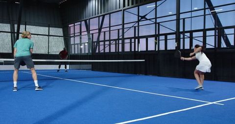 Diverse padel players competing in indoor doubles match