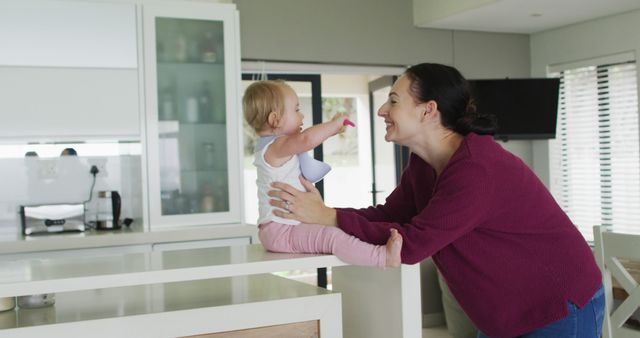 Mother Smiling While Feeding Baby in Modern Kitchen - Download Free Stock Images Pikwizard.com