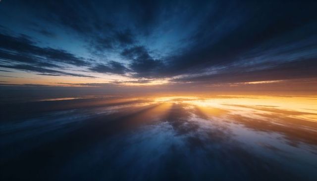 Golden sunrise beaming across mirror-like ocean with dramatic layered clouds