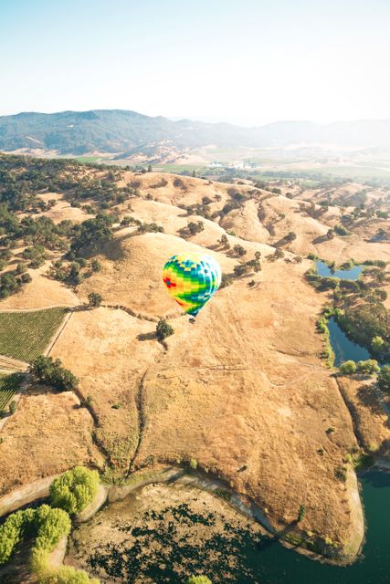 Hot air balloon gently drifting over a dry, scenic landscape. Great for travel and adventure-related promotions, summer activities, outdoor fun, or countryside exploration themes.