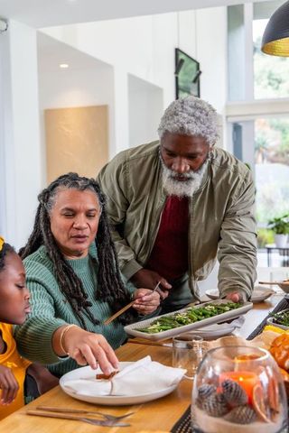 Senior African American family sharing healthy greens around wooden dining table