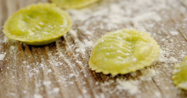 Freshly made ravioli pasta is dusted with flour on a wooden surface, showcasing the process of Italian cooking. Homemade pasta signifies the tradition and skill involved in creating authentic Italian cuisine.