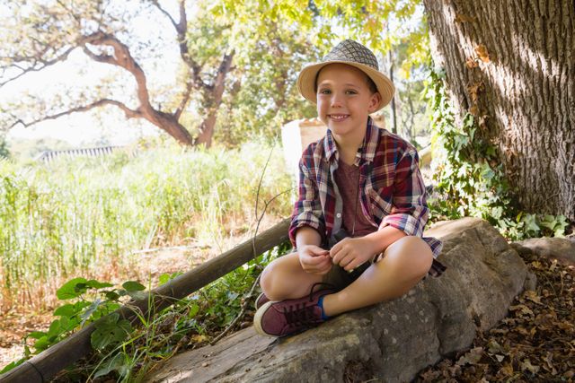 Portrait of smiling boy sitting on the rock in the forest