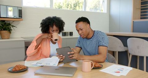 Couple collaborating on finance with tablet over breakfast