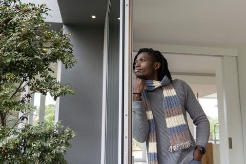African american man standing in modern doorway looking outward wearing striped knit scarf