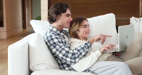 Couple Relaxing Together with Laptop on Comfortable Couch