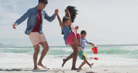 Happy Family Walking and Playing on Sunny Beach
