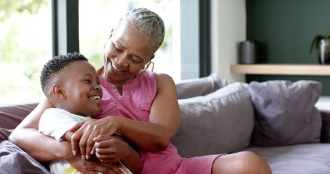 Joyful Grandmother Cuddling Grandson on Sofa in Welcoming Living Room