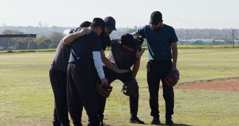 Baseball team huddling on grass field showing teamwork camaraderie and pregame focus