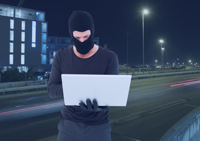 Depicts a cybercriminal wearing a black balaclava while using a laptop in an urban night setting. Represents concepts like cybersecurity, cybercrime, hacking, and digital threats. Suitable for articles on internet security, high-tech criminal activities, and urban crime prevention.