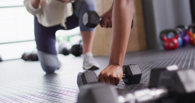 Close-up view of individuals engaging in strength training with dumbbells. This image showcases determination and commitment to fitness. Ideal for fitness blogs, gym promotions, workout programs, and health-related articles.