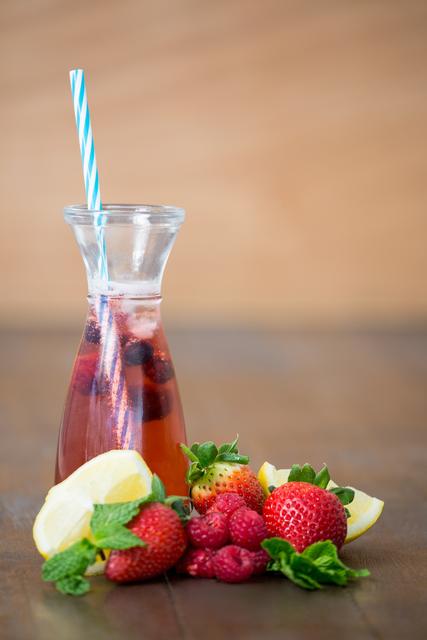 Bottle with berry cocktail and berry fruits on wooden board