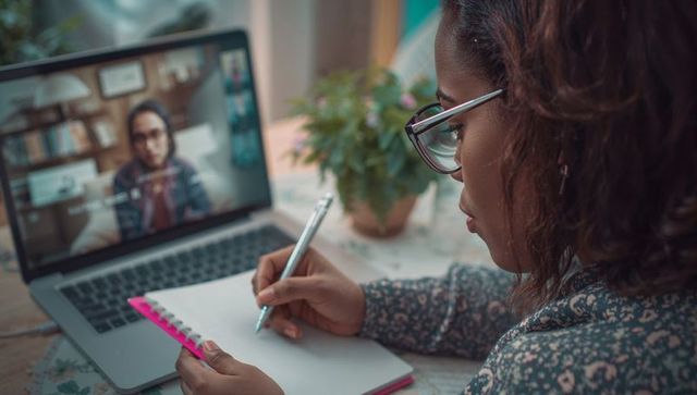 Woman engaged in video call at home office with notebook
