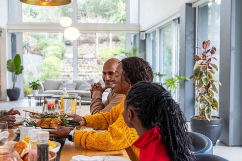 Diverse Family Sharing Roast Chicken at Bright Modern Open-Plan Dining Table