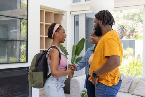 African american family greeting teen daughter returning home from college with backpack