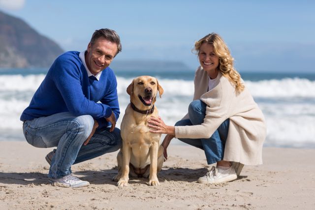 Mature couple enjoying a day at the beach with their Labrador Retriever. They are petting the dog while smiling, with the ocean waves in the background. Ideal for use in advertisements, travel brochures, pet care promotions, and lifestyle blogs.