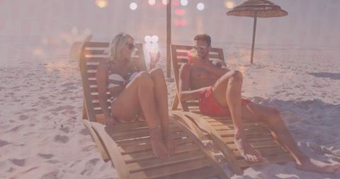 Couple relaxing on beach with cocktails in summer