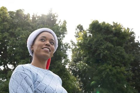 African American woman wearing Santa hat in sunlit park portrait for holiday marketing