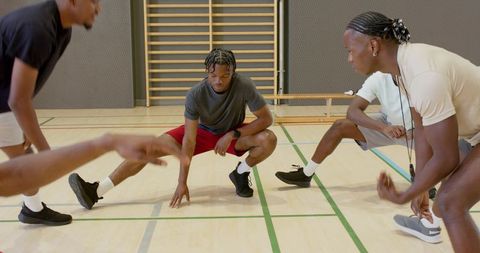 African american men performing side lunges on gym court preparing for team training