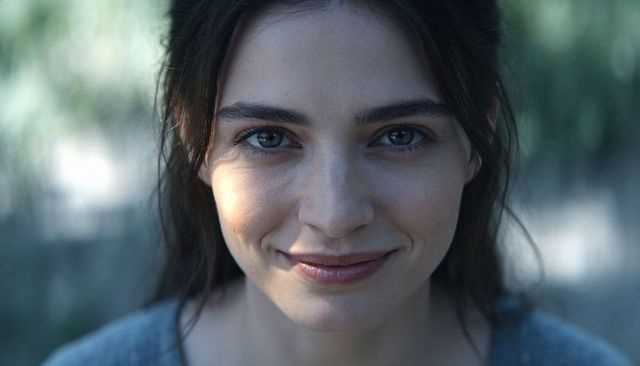 Smiling young woman with freckles in soft natural light closeup portrait, direct gaze