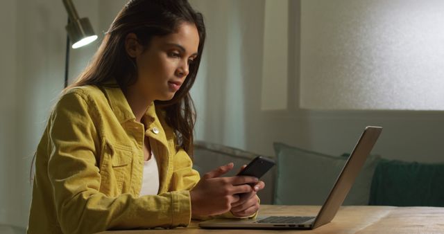 Young Woman Using Smartphone While Working on Laptop at Home - Download Free Stock Images Pikwizard.com