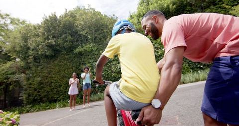 Father Teaching Son to Ride Bicycle Outdoors in Summer