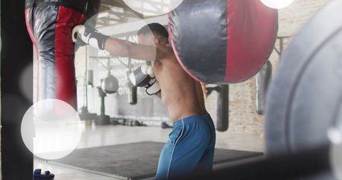 Boxer training on heavy bag in urban gym, punching for strength and endurance