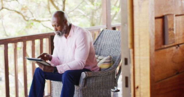 Senior african american man on balcony in log cabin using tablet. Log cabin and lifestyle concept.