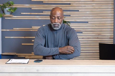 Senior african american receptionist checking clipboard at modern wooden front desk