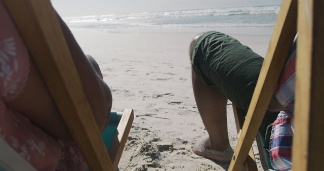 Couple enjoying leisure time sitting on wooden chairs by the ocean. Ideal for vacation promotions, travel brochures, summer getaway advertisements, and lifestyle blogs.