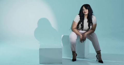 Chic Woman in Fashionable Outfit Under Spotlight in Aquatic Studio