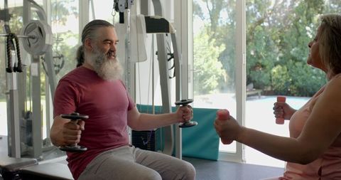 Senior Couple Exercising Together with Dumbbells in Gym