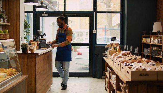 Bakery barista preparing espresso at wooden counter with croissants and rustic display