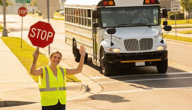 Crossing guard holding stop paddle stopping school bus in residential school zone