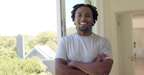 Confident african american man smiling with arms crossed in bright minimalist home interior