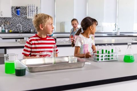 Elementary students conducting colorful science experiments with test tubes in school lab
