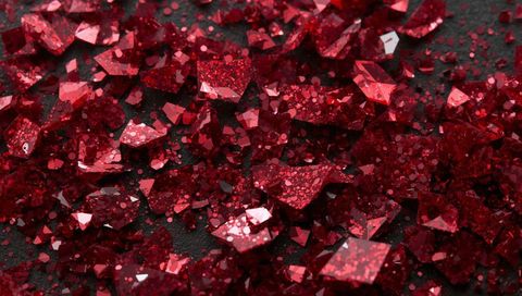 Shimmering red crystal shards scattering across dark textured surface