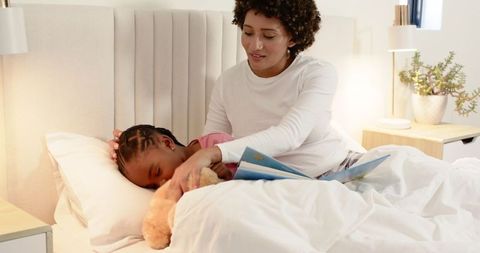 Mother Reading Bedtime Story to Child with Teddy Bear