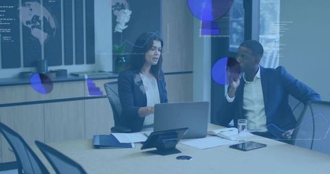Mid-adult professionals collaborating on laptop with data visualizations in modern conference room