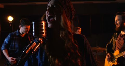 Energetic band rehearsing in studio with microphone