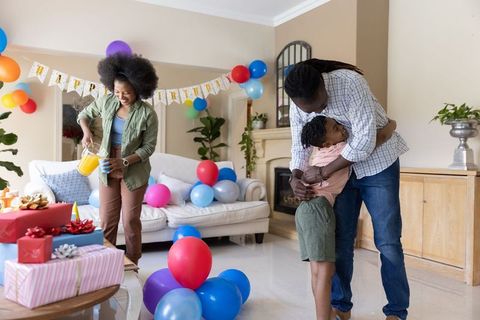 Joyful african american family birthday celebration parents hugging child woman pouring juice