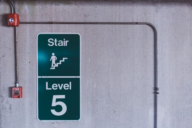 Stair Level 5 sign mounted on concrete wall in industrial building, useful for illustrating emergency exit routes, safety information in commercial buildings, and navigation aids in parking structures.