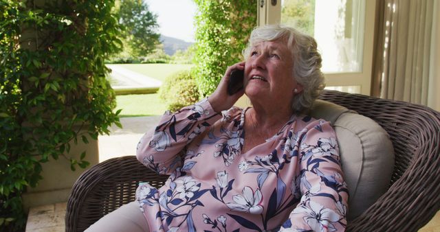 Caucasian senior woman talking on smartphone while sitting on the chair outdoors. retirement senior lifestyle living concept