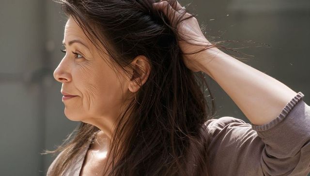 Contemplative middle-aged woman brushing hair profile portrait in soft natural light serene