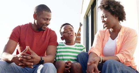 African american parents listening to son on porch steps, casual family conversation
