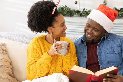 African american couple sharing cozy holiday moment reading and sipping cocoa