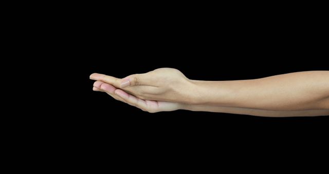 A Caucasian hand is extended with an open palm against a black background, with copy space. It suggests a gesture of offering, assistance, or presenting something invisible.