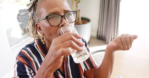 Senior Woman Taking Medication with Glass of Water at Home